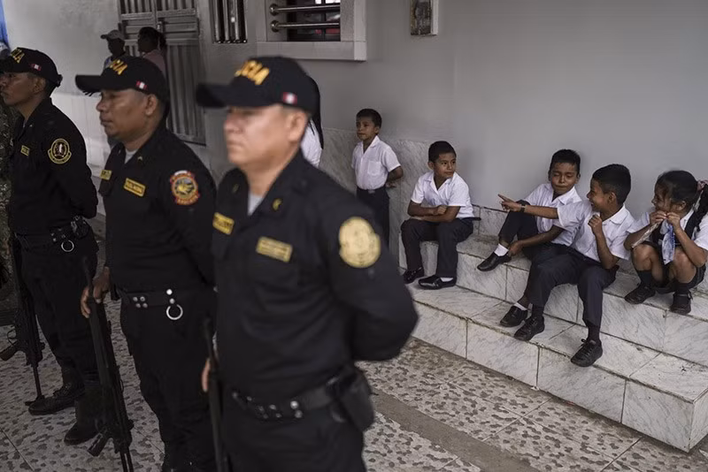 Học sinh ngồi phía sau cảnh sát Peru đang xếp hàng cho lễ thượng cờ tại Santa Rosa, Peru. (Ảnh: AP) chum-anh-cuoc-song-o-dao-santa-rosa-011.jpg