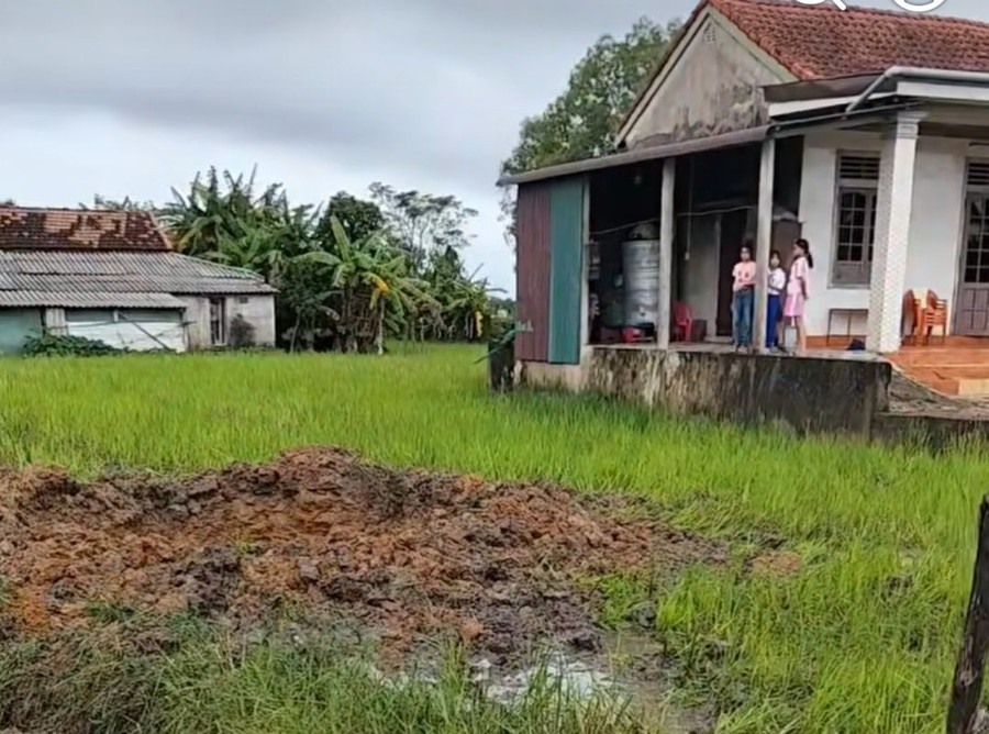 Hố sâu giữa ruộng sau vụ nổ lớn, nghi do bom sót lại.