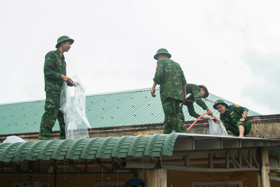 Bộ đội biên phòng hỗ trợ giáo viên chằng chống, gia cố mái trường. Ảnh; Trần Cường truong-hoc-chong-bao-4.jpg