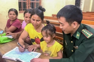 Cán bộ Biên phòng hướng dẫn học viên lớp xóa mù chữ. (Ảnh: CSCC)