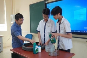 Thầy giáo Dương Quốc Trọng (bên trái) hướng dẫn học trò thực hiện dự án khoa học kỹ thuật.