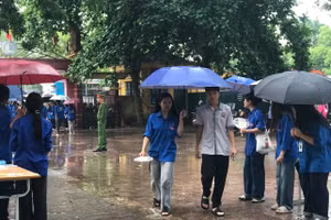 Thanh niên tình nguyện "đội mưa" hỗ trợ thí sinh vào khu vực phòng thi.