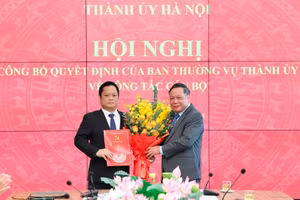 Phó Bí thư Thường trực Thành ủy Hà Nội Nguyễn Văn Phong trao quyết định và tặng hoa chúc mừng ông Vũ Minh Tuấn. Ảnh: Q.T