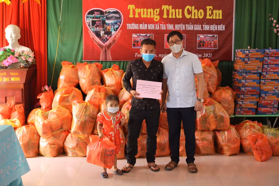 Ông Đỗ Văn Sơn (bên phải) trao quà cho phụ huynh có học sinh bị bỏng nặng.