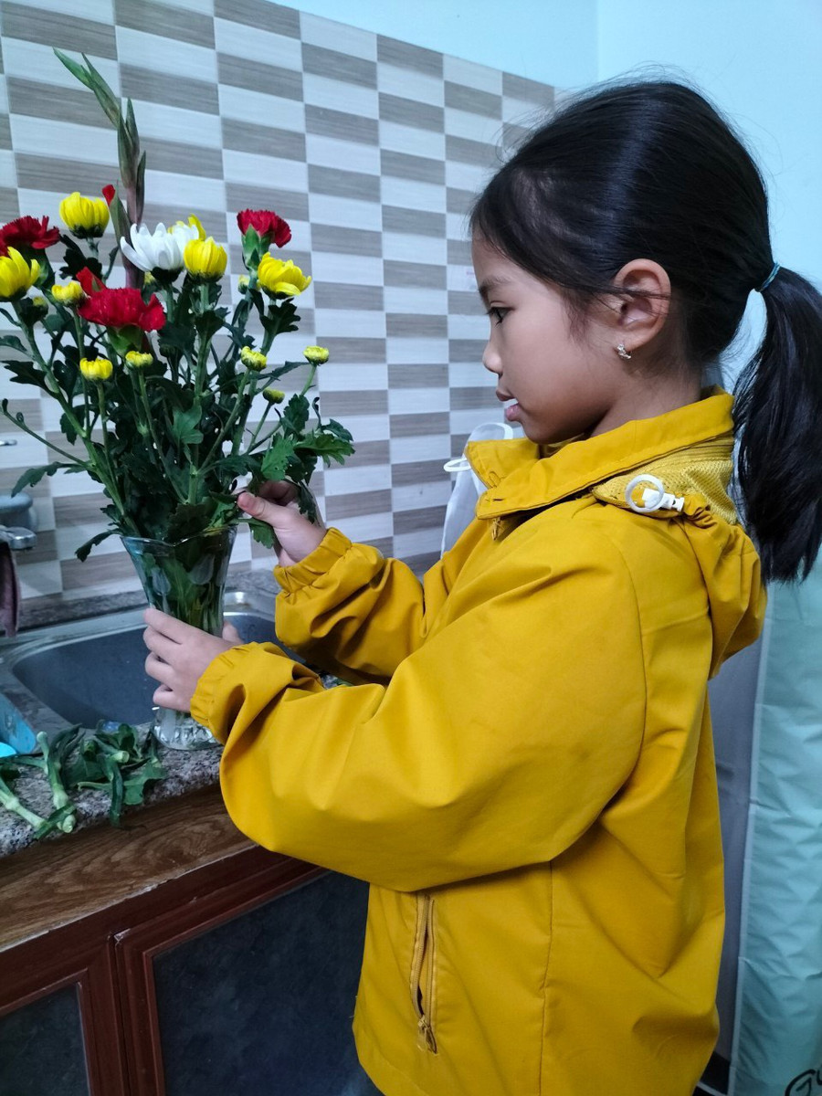 Học sinh Trường Tiểu học Hải Xuân giúp bố mẹ cắm hoa ngày Tết tại gia đình.