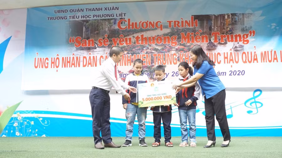 Ông Trịnh Văn Hào và bà Hoàng Tú Anh trao học bổng Vì Mái Trường Xanh cho các em học sinh trường Tiểu học Phương Liệt.