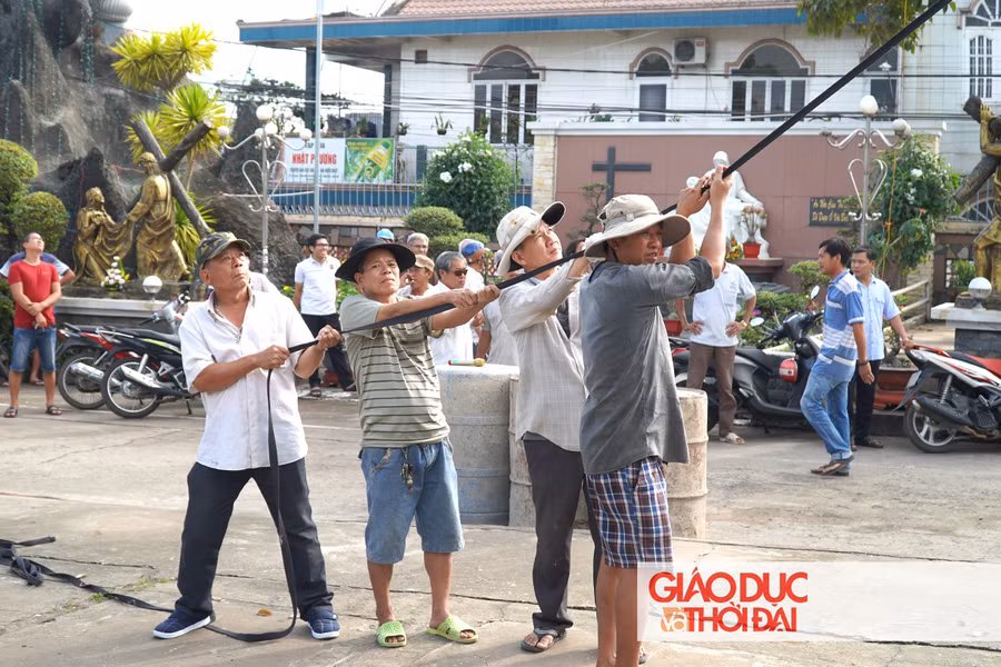 Người dân tại giáo xứ Bùi Chu đang cùng nhau kéo ngôi sao Giáng sinh lên tháp chuông của nhà thờ.