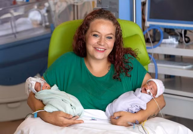 Bà mẹ bế con trai và con gái song sinh trên tay