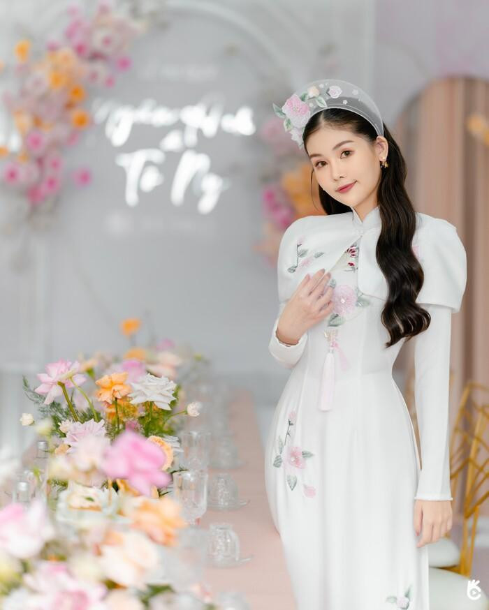 Hoa hậu Ngân Anh diện áo dài truyền thống thêu hoa tinh tế và được cách điệu phần khoác vai.Cô dâu nhận về &quot;cơn mưa lời khen&quot; với hình ảnh xinh đẹp, tươi tắn.