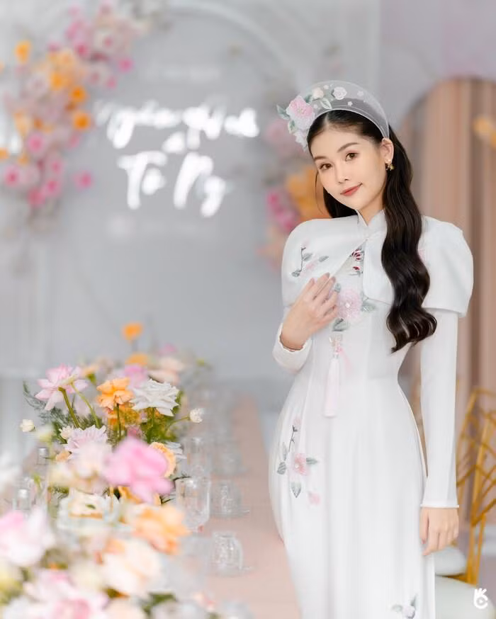 Hoa hậu Ngân Anh diện áo dài truyền thống thêu hoa tinh tế và được cách điệu phần khoác vai.Cô dâu nhận về "cơn mưa lời khen" với hình ảnh xinh đẹp, tươi tắn.