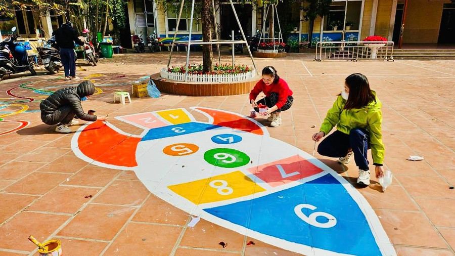 Các cô giáo tô vẽ những hình khối trên sân để học sinh tham gia vận động thể chất.