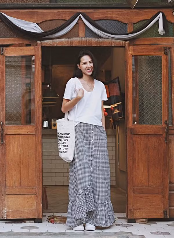 Áo thun trắng được sao Việt lựa chọn bởi dễ sử dụng và thoải mái phối đồ cùng nhiều kiểu dáng quần jean, chân váy midi, maxi, váy ngắn khác nhau. Minh Triệu với hình ảnh phóng khoáng và tự do cùng cách phối áo hợp mốt đi cùng chân váy maxi, túi vải đeo vai.
