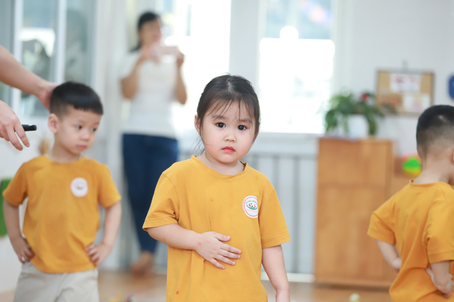 Cô giáo hướng dẫn trẻ lớp Nhà trẻ hoạt động phát triển vận động đi bước qua chướng ngại vật.