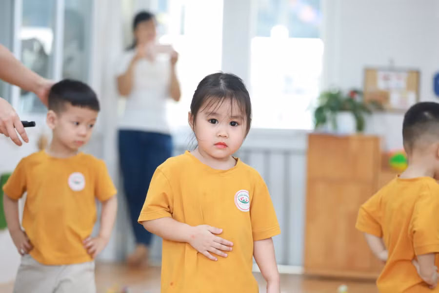 Cô giáo hướng dẫn trẻ lớp Nhà trẻ hoạt động phát triển vận động đi bước qua chướng ngại vật.