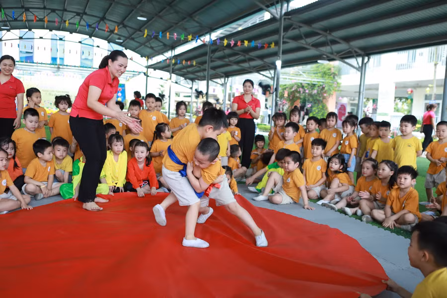 Trẻ tham gia đấu Vật để rèn luyện sức khỏe dưới sự cổ vũ của cô và các bạn.