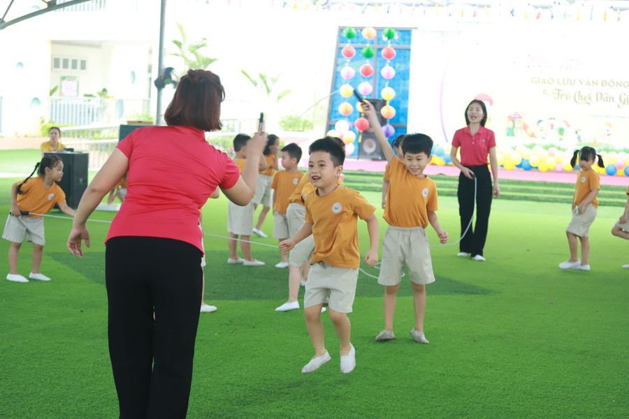 Cô và trẻ cùng nhau tham gia trò chơi Nhảy dây dưới sân trường.