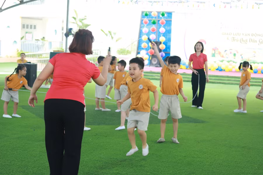 Cô và trẻ cùng nhau tham gia trò chơi Nhảy dây dưới sân trường.