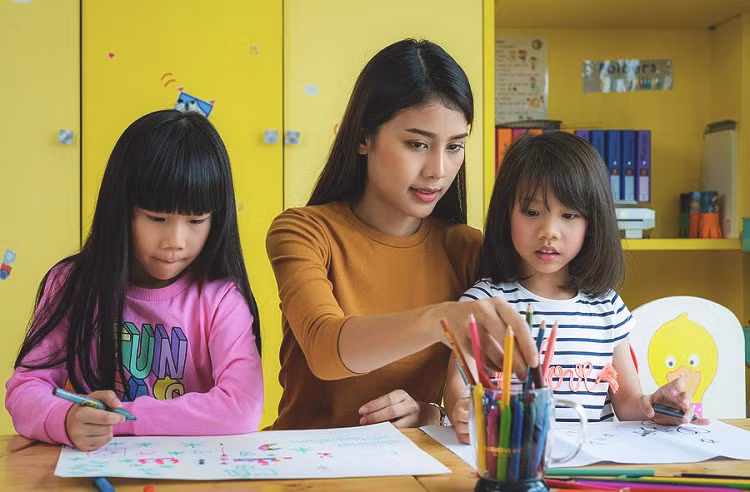 Giáo viên mầm non dạy trẻ vẽ. Ảnh: Pixels