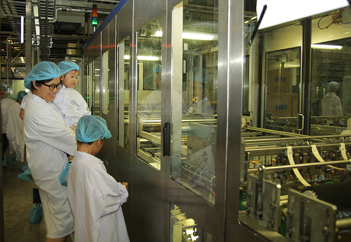 Bé thích thú khi được mẹ giới thiệu về dây chuyền đóng gói sữa Bé thích thú khi được mẹ giới thiệu về dây chuyền đóng gói sữa