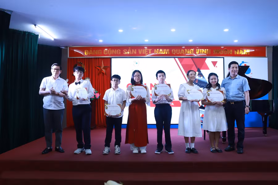 Nhà báo, nhạc sĩ Vũ Hồ Tùng (bìa trái) trao giải Nhất cho thí sinh Bùi Chí Bách lớp 8E.