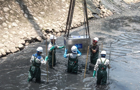 Công nhân đưa công nghệ Nano - Bioreactor xuống xử lý ô nhiễm sông Tô Lịch. Ảnh: IT.