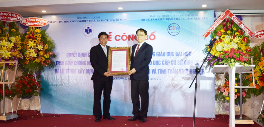 PGS.TS Nguyễn Xuân Hoàn nhận chứng nhận đạt kiểm định chất lượng từ PGS.TS Nguyễn Hội Nghĩa - Giám đốc Trung tâm kiểm định chất lượng giáo dục ĐHQG TPHCM