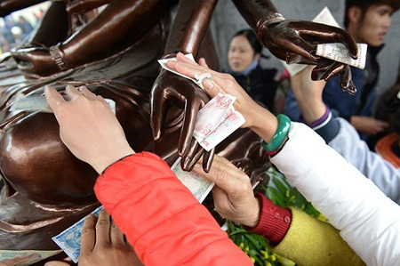 Nhét đầy tiền lẻ vào tay Phật.