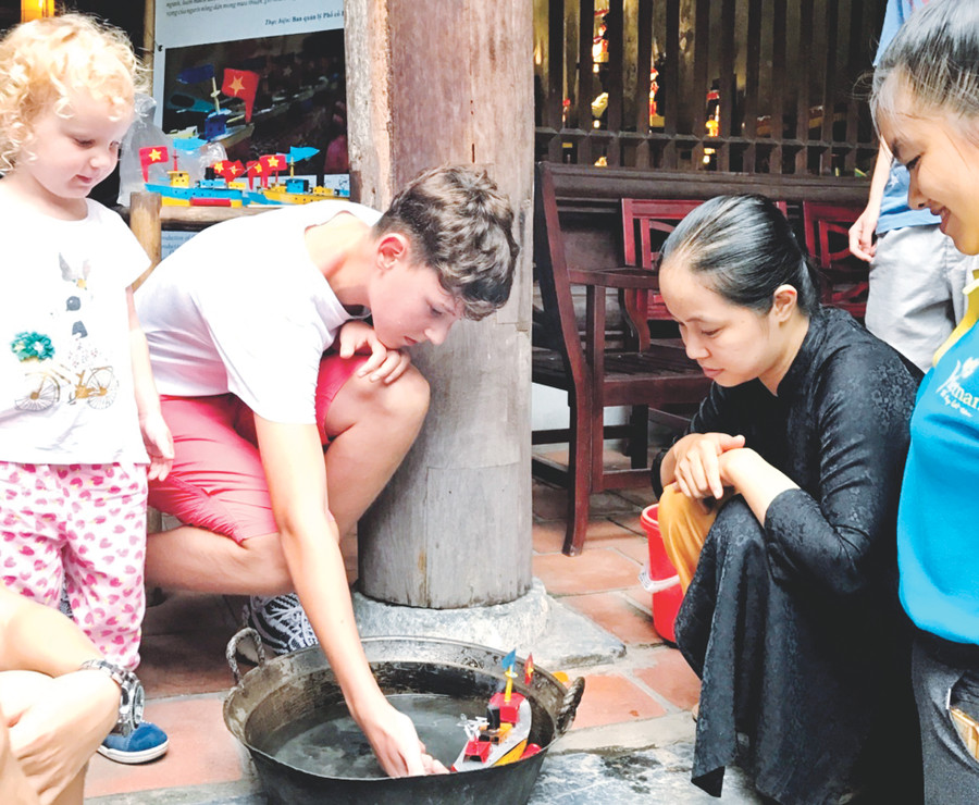 Giới thiệu cách chơi tàu thủy sắt với du khách tại Đình Kim Ngân (phố Hàng Bạc, Hà Nội)