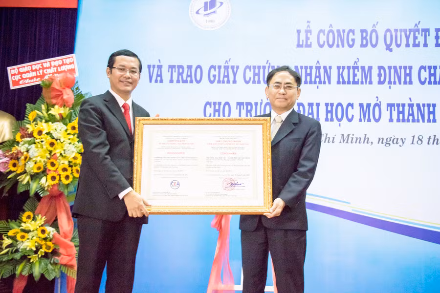 PGS.TS Nguyễn Hội Nghĩa-Phó Giám đốc ĐHQG TPHCM (phải) trao giấy chứng nhận đạt chuẩn kiểm định cho PGS.TS Nguyễn Văn Phúc-Hiệu trưởng nhà trường