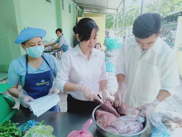 Lãnh đạo trường phụ trách bán trú đang cùng nhân viên y tế và nhân viên cấp dưỡng đang kiểm tra thực phẩm