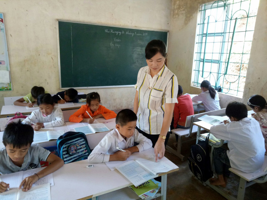 Cô giáo Vi Thị Chuyên ân cần chỉ dạy cho học sinh của mình ở lớp học tại bản Cha Khót. Ảnh: T.G