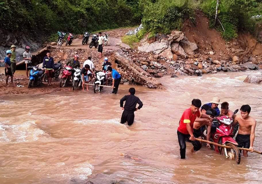 Dân bản khiêng xe qua suối giúp cô giáo Vi Thị Chuyên và Hà Thị Hằng. Ảnh: T.g