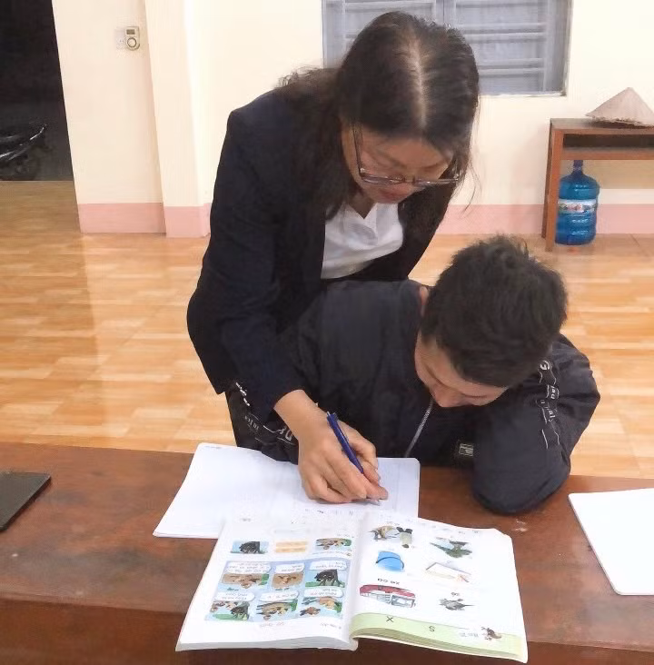 Cô giáo tận tình dạy học viên cách viết chữ.