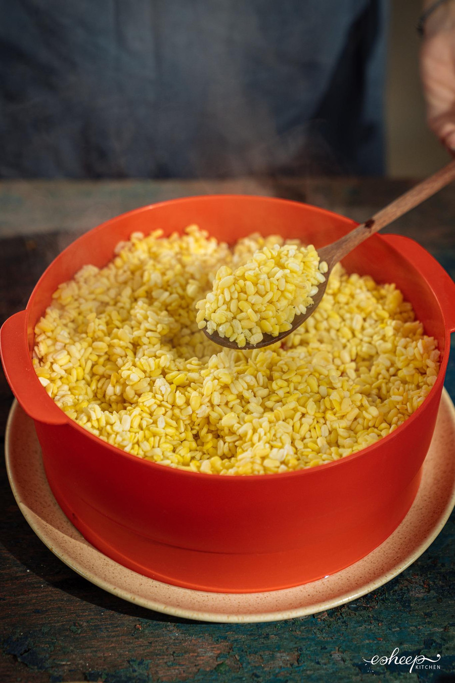 Đậu xanh để làm xôi cốm hạt sen, bạn ngâm nước ấm cho nở rồi trộn với xíu muối và hấp cùng lá nếp cho chín.