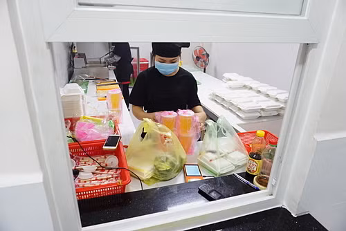 Một gian bếptrong căn bếp trung tâmtại Thủ Đức nhìn qua ô cửa giao hàng. Ảnh: Viễn Thông