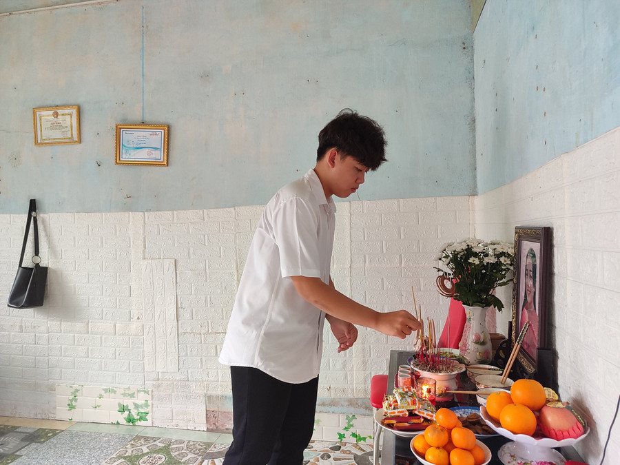 Con trai lớn của cô Hạnh đang học lớp 12, thắp hương bên bàn thờ tang mẹ.