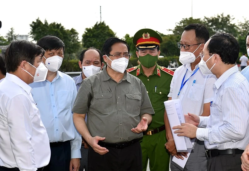 Thủ tướng Phạm Minh Chính nghe lực lượng chức năng báo cáo việc thực hiện Chỉ thị 16 tại phường Tân Phú, TP. Thủ Đức, TPHCM, ngày 11/7 - Ảnh: VGP