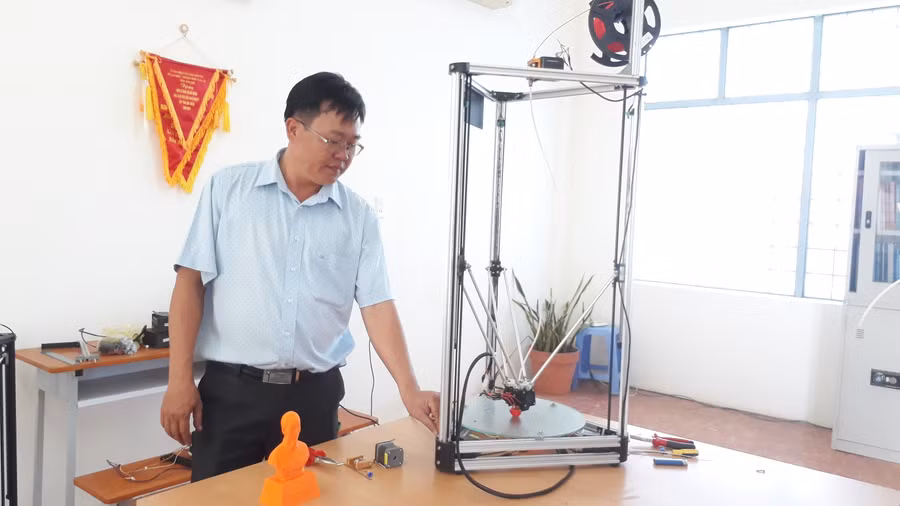 Thầy Hoàng và máy in 3D giá rẻ của nhóm nghiên cứu. Ảnh: Trúc Hân