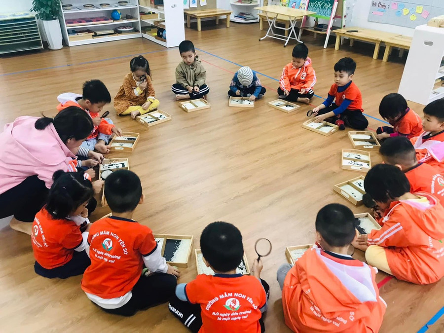 Với chiếc kính lúp trên tay, trẻ biết được hình dạng khác nhau của hạt gạo nếp - gạo tẻ trong khay đựng.