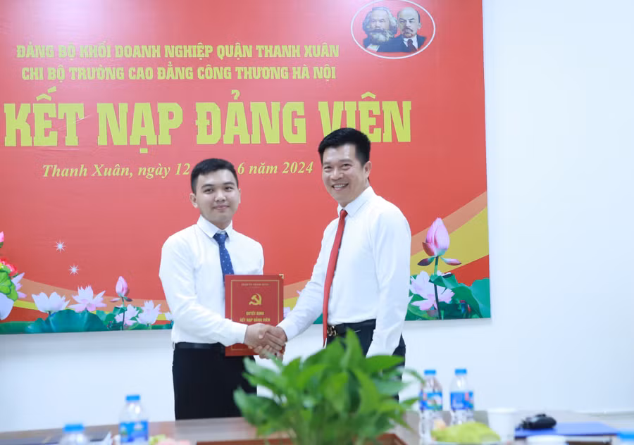 Ông Nguyễn Văn Minh (phải) - Bí thư Đảng ủy khối doanh nghiệp quận Thanh Xuân chúc mừng tân Đảng viên trẻ Phi Hồ Hải.