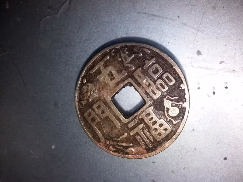 Đồng tiền này được gỡ ra từ phía dưới bụng tượng kim loại. Ảnh: CTV.