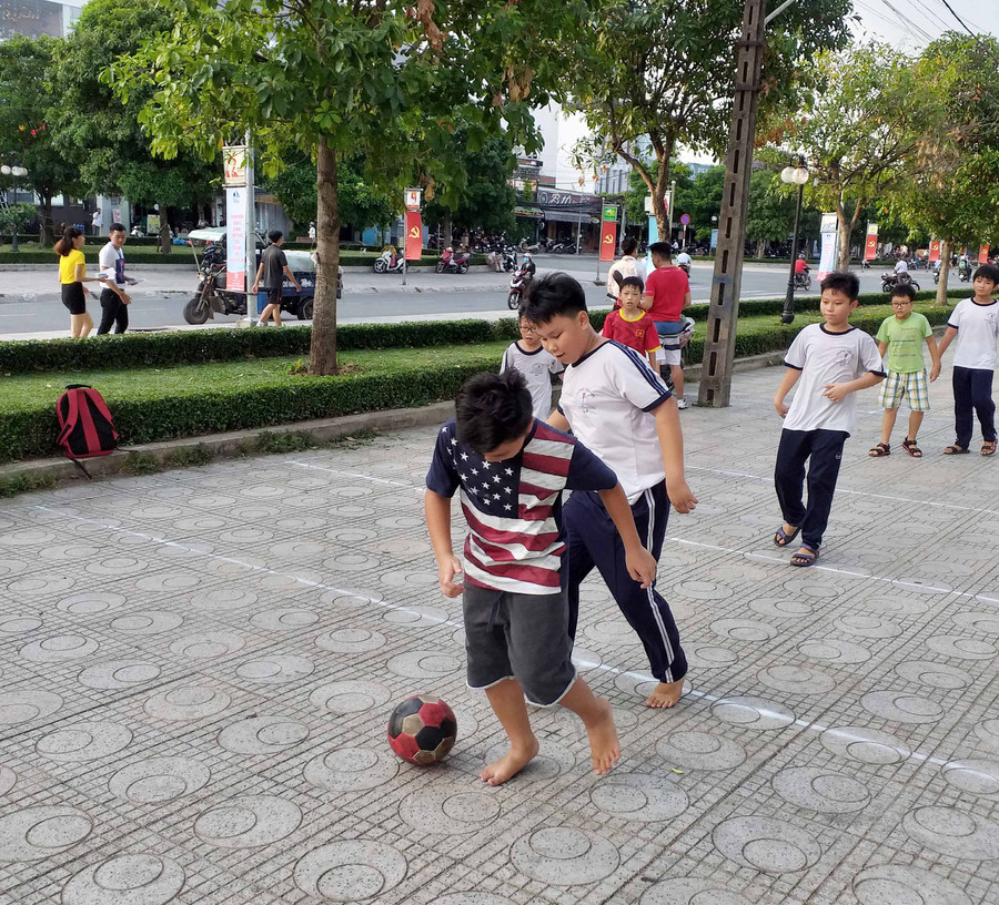 Trẻ em vô tư đá bóng ven đường