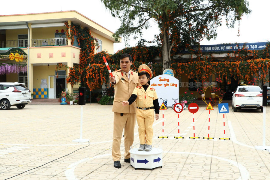 Cán bộ Đội Cảnh sát giao thông huyện Đại Từ, tỉnh Thái Nguyên hướng dẫn trẻ thực hiện hiệu lệnh của người điều khiển giao thông.