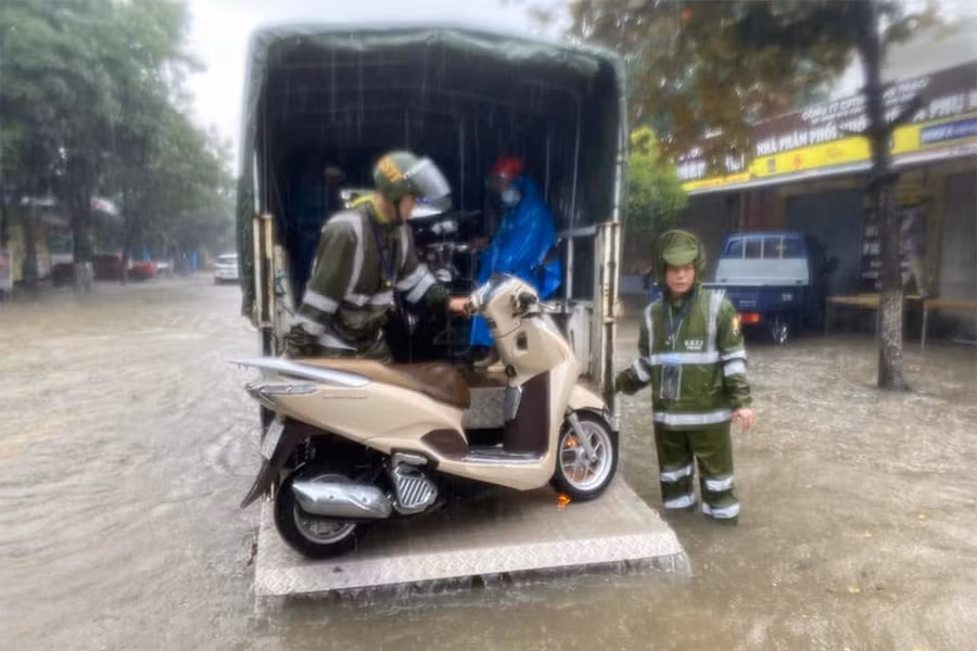 Lực lượng cảnh sát giao thông hỗ trợ đưa xe máy của người dân bị chết máy đến nơi khô ráo.