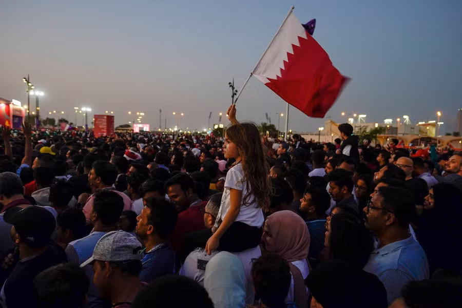 Một cổ động viên nhí đang giơ cao lá cờ Qatar.