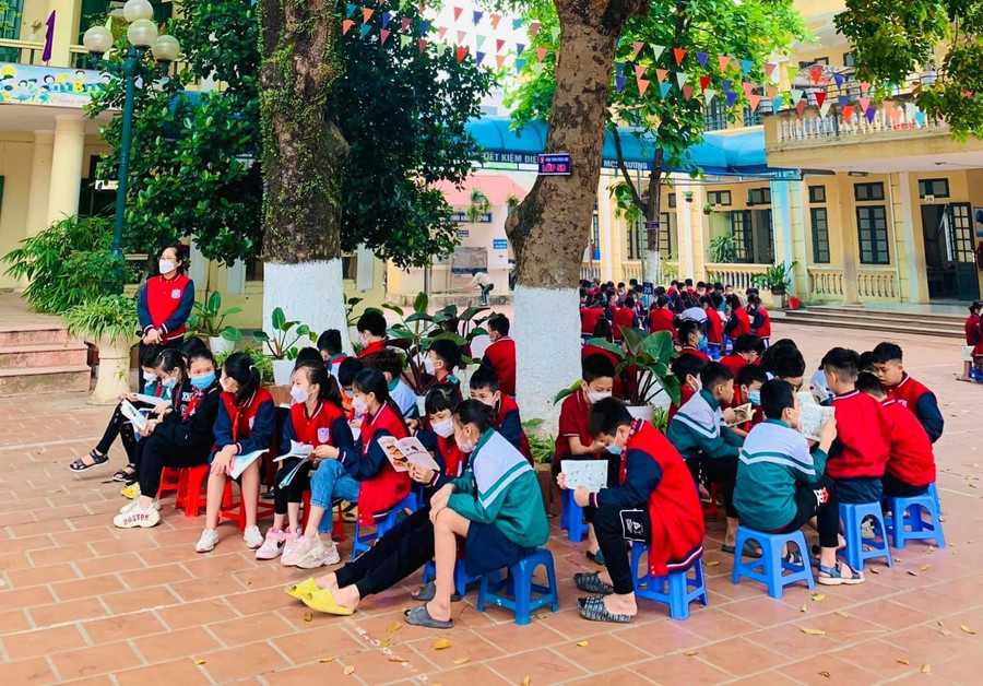 Học sinh Trường Tiểu học Lê Lợi đọc sách ngoài sân trường.