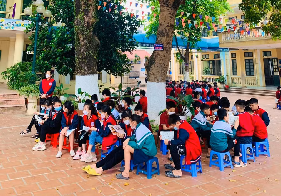 Học sinh Trường Tiểu học Lê Lợi đọc sách ngoài sân trường.