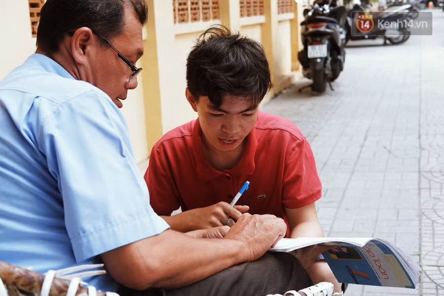 Lớp học đáng yêu trên vỉa hè: Một bác bảo vệ vừa giữ xe vừa dạy chữ cho cậu nhóc bán hàng rong ở Sài Gòn - Ảnh 1.