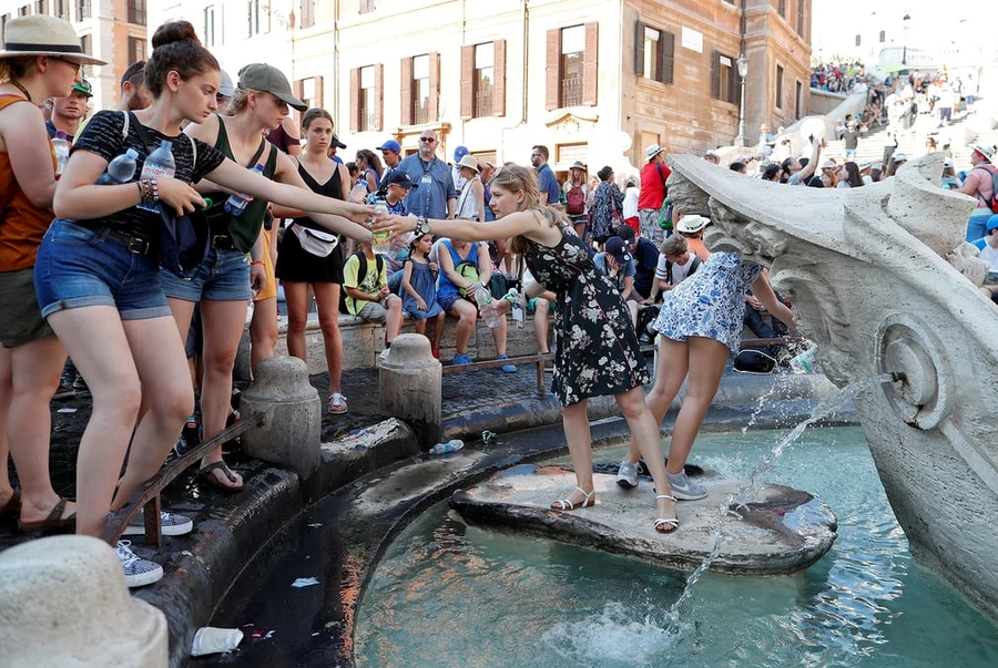 Khách du lịch lấy nước từ đài phun nước Barcaccia gần Quảng trường Piazza di Spagna, Italy