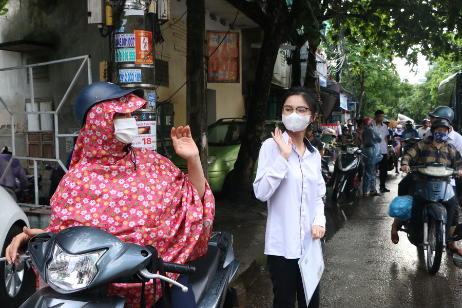 Mẹ đưa con đến trường thi khi có mưa rào đầu giờ sáng tại Trường THPT Ngô Quyền, TP Nam Định.